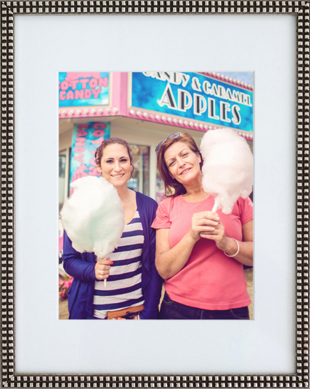 a framed photograph of a mother and daughter both wearing brightly colored clothing and pretty pastel cotton candy puffs that are cloudlike.